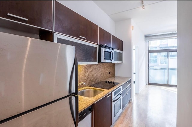 kitchen featuring sink, light wood-type flooring, appliances with stainless steel finishes, light stone countertops, and backsplash