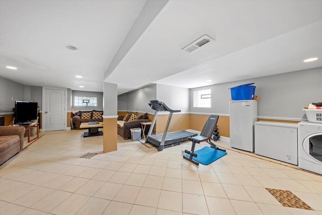 exercise room featuring washer / clothes dryer and light tile patterned floors