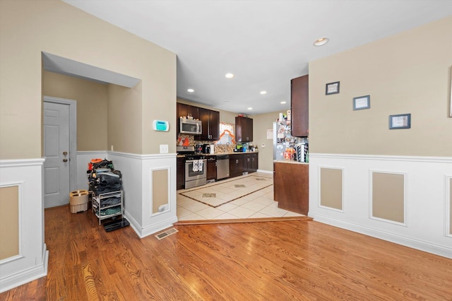 kitchen featuring dark brown cabinets, light hardwood / wood-style floors, and appliances with stainless steel finishes