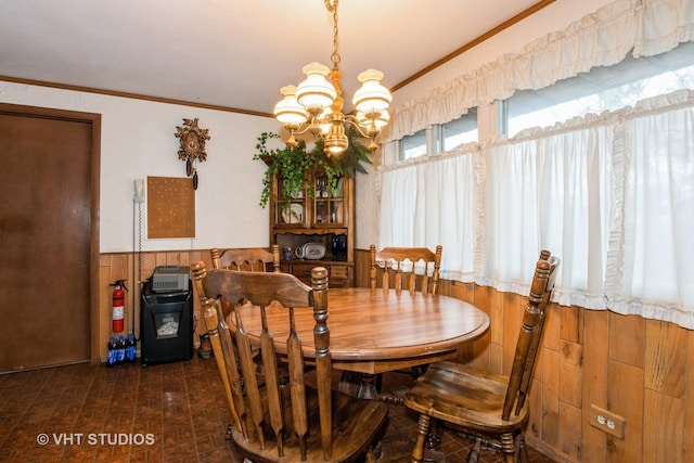 dining room with an inviting chandelier, ornamental molding, and wooden walls