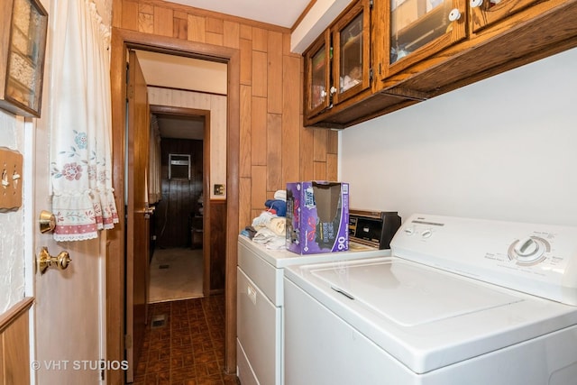 washroom featuring cabinets, washer and clothes dryer, and wood walls