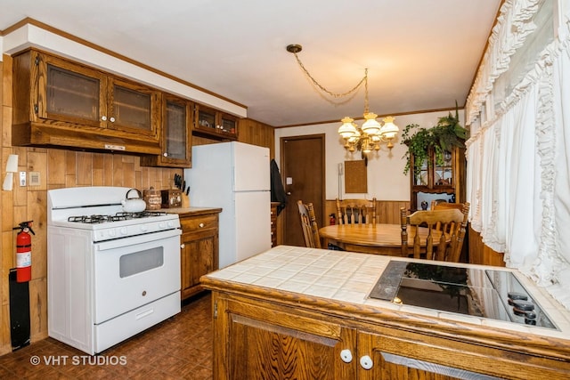 kitchen with wood walls, ornamental molding, a notable chandelier, pendant lighting, and white appliances