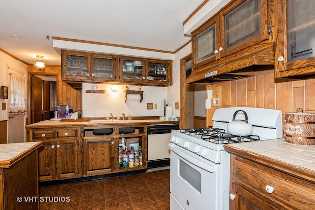 kitchen featuring tile countertops, wooden walls, sink, ornamental molding, and white appliances