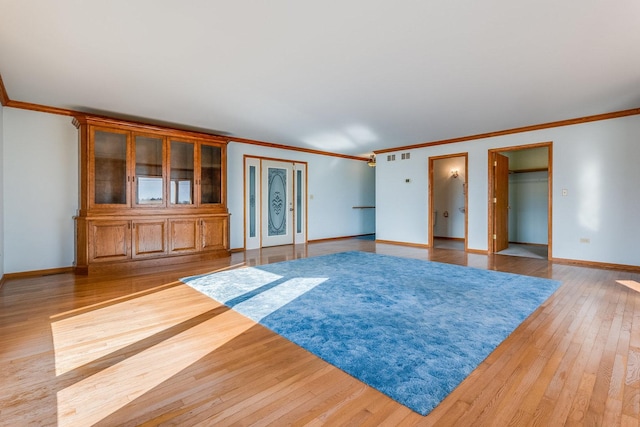 unfurnished living room featuring hardwood / wood-style flooring and ornamental molding