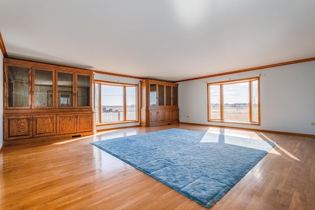 unfurnished living room with light hardwood / wood-style flooring, plenty of natural light, and ornamental molding