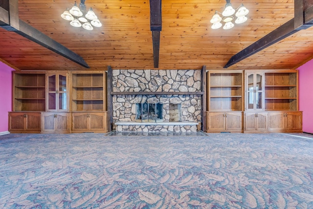 unfurnished living room featuring beam ceiling, a chandelier, carpet floors, and a stone fireplace