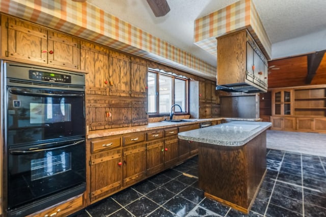 kitchen with a kitchen island, sink, black double oven, ceiling fan, and a textured ceiling