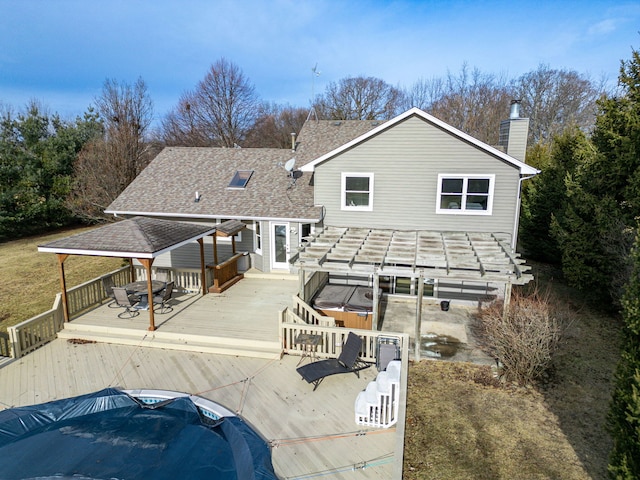 back of property featuring a wooden deck and a jacuzzi