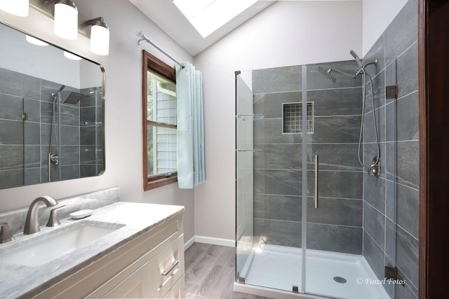 bathroom featuring vanity, hardwood / wood-style floors, a shower with door, and vaulted ceiling with skylight