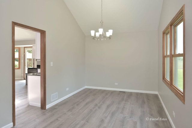 empty room with lofted ceiling, a chandelier, and light wood-type flooring