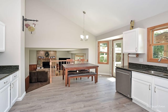 kitchen with sink, hanging light fixtures, dishwasher, dark stone counters, and white cabinets