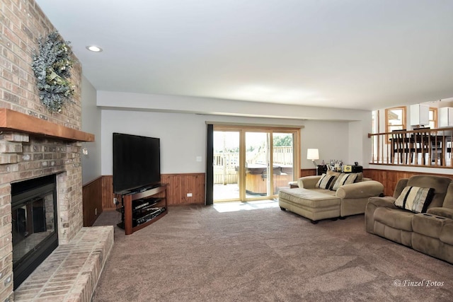 living room with carpet floors, a fireplace, and wood walls