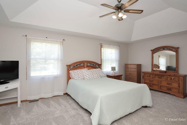 bedroom featuring a tray ceiling, vaulted ceiling, light colored carpet, and ceiling fan