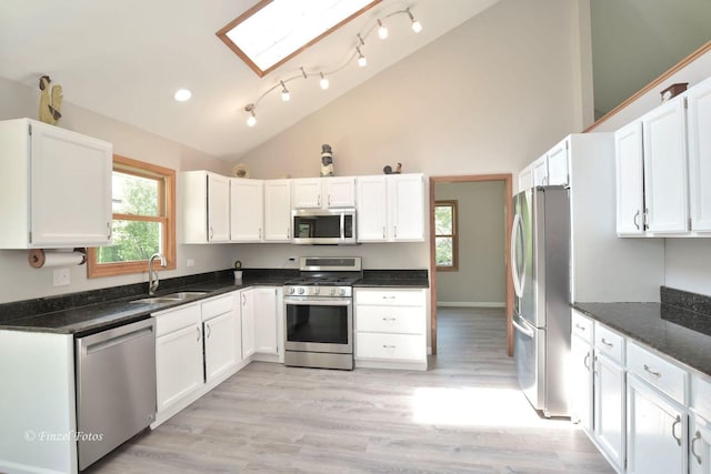 kitchen featuring stainless steel appliances, white cabinetry, sink, and dark stone countertops