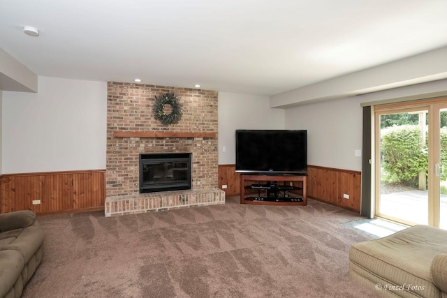 carpeted living room featuring a fireplace and wooden walls