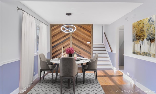 dining room with hardwood / wood-style flooring, a chandelier, and wood walls