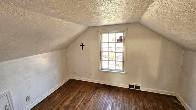 bonus room with vaulted ceiling, dark wood-type flooring, and a textured ceiling