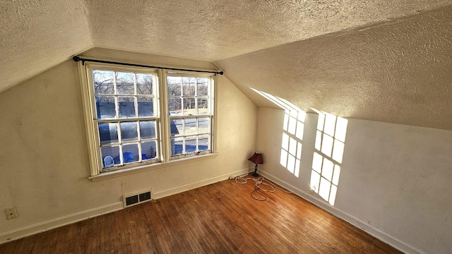 bonus room with hardwood / wood-style flooring, vaulted ceiling, a textured ceiling, and a wealth of natural light