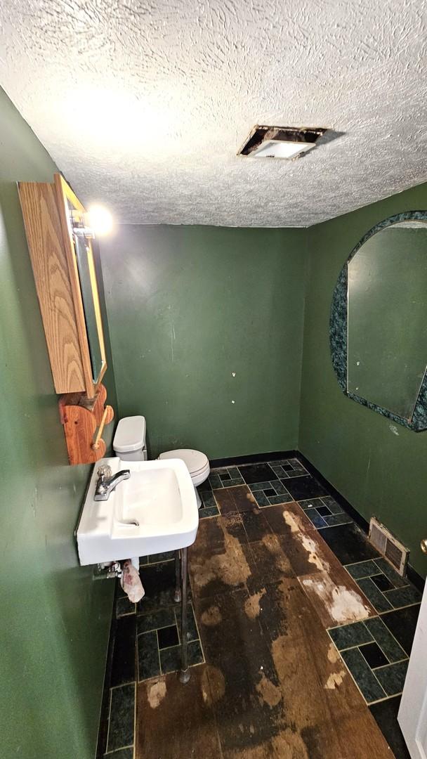 bathroom with sink, toilet, and a textured ceiling