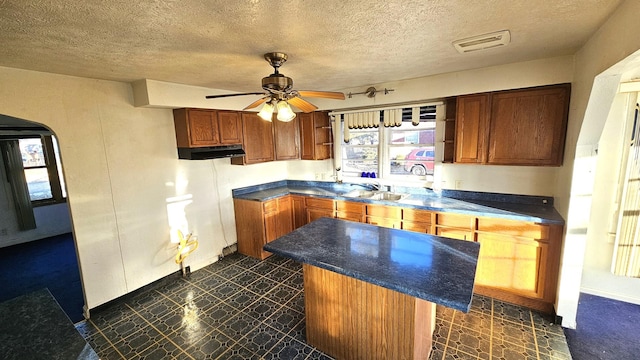 kitchen with a kitchen island, sink, a textured ceiling, and ceiling fan