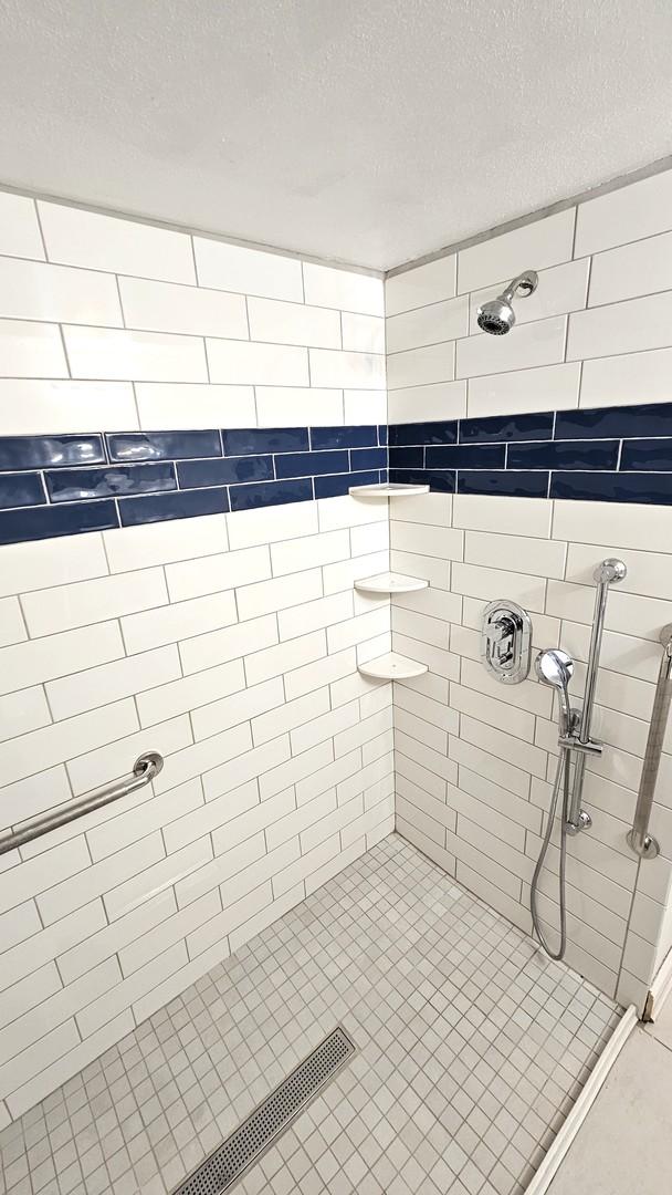 bathroom featuring tiled shower and a textured ceiling