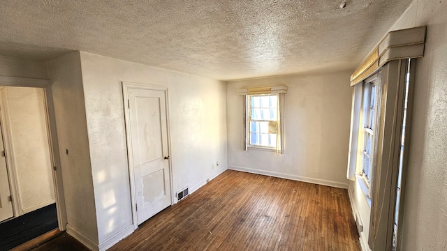 spare room featuring dark hardwood / wood-style floors and a textured ceiling