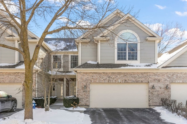 traditional home featuring a garage, brick siding, and aphalt driveway