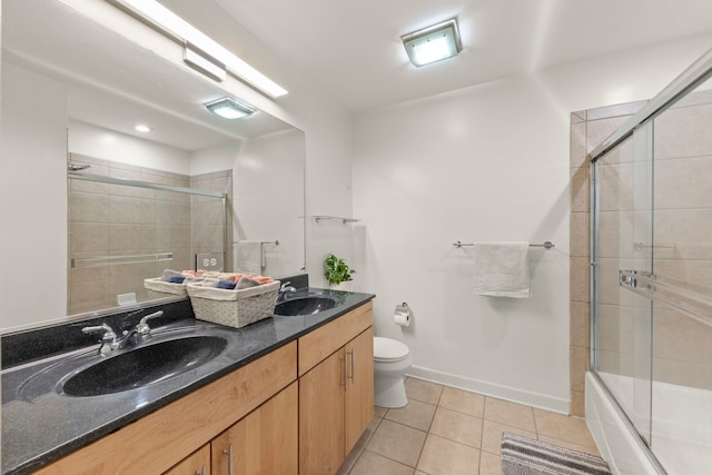 bathroom featuring bath / shower combo with glass door, a sink, toilet, and tile patterned floors