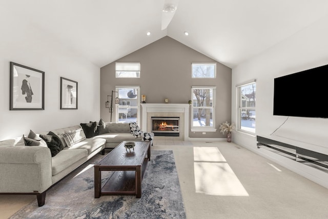 living area featuring high vaulted ceiling, a tile fireplace, light carpet, and baseboards