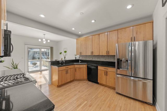 kitchen with a peninsula, a sink, black dishwasher, light brown cabinetry, and stainless steel fridge