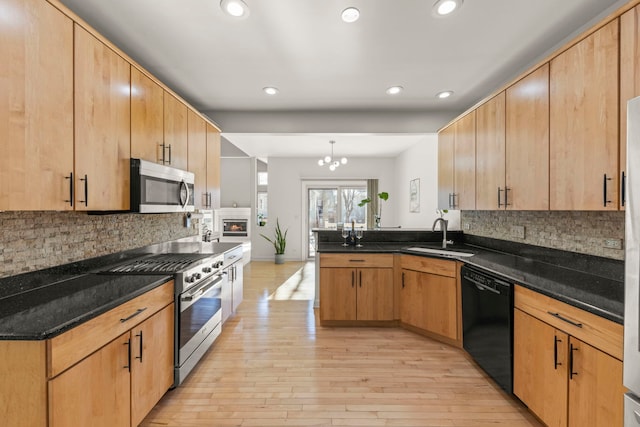 kitchen with appliances with stainless steel finishes, pendant lighting, a sink, and dark stone countertops