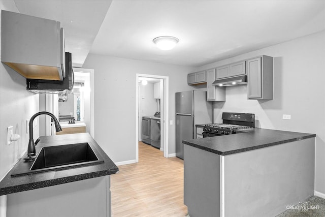 kitchen with black stove, sink, washer and dryer, kitchen peninsula, and gray cabinets