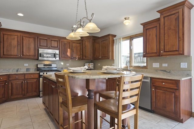 kitchen featuring tasteful backsplash, decorative light fixtures, light tile patterned floors, appliances with stainless steel finishes, and light stone countertops