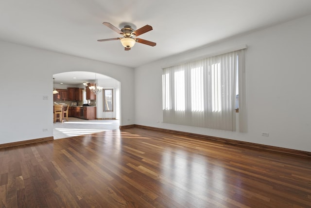 unfurnished living room with ceiling fan with notable chandelier and dark hardwood / wood-style floors