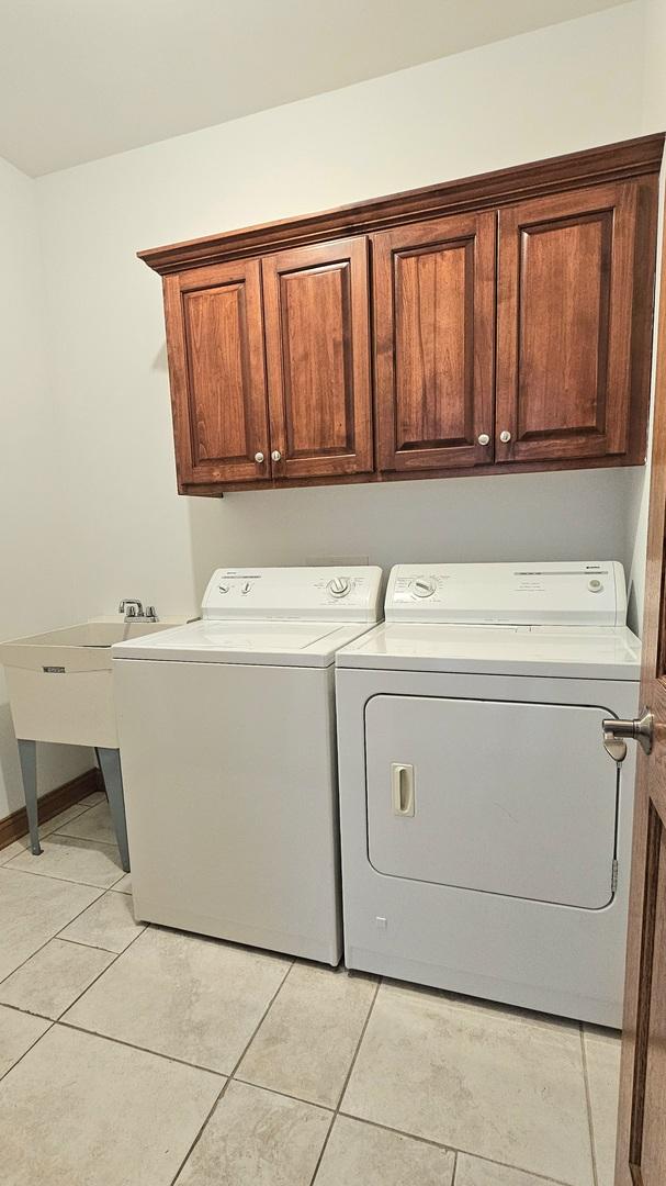 washroom with cabinets, washing machine and dryer, sink, and light tile patterned floors