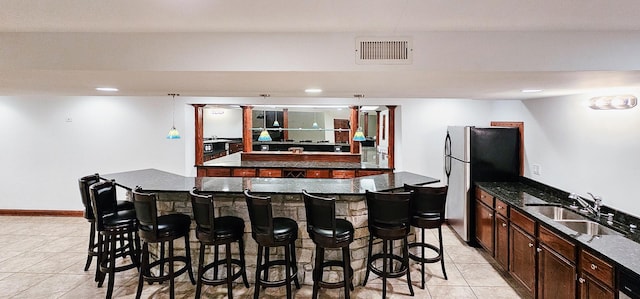 kitchen featuring a kitchen island, sink, stainless steel fridge, and a kitchen bar