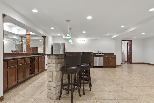 interior space featuring pendant lighting, light tile patterned floors, stainless steel appliances, and dark brown cabinetry