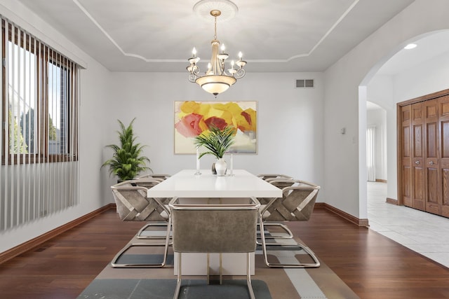 dining area featuring a chandelier, dark hardwood / wood-style flooring, and a raised ceiling