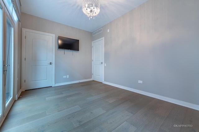 unfurnished bedroom featuring an inviting chandelier and light wood-type flooring