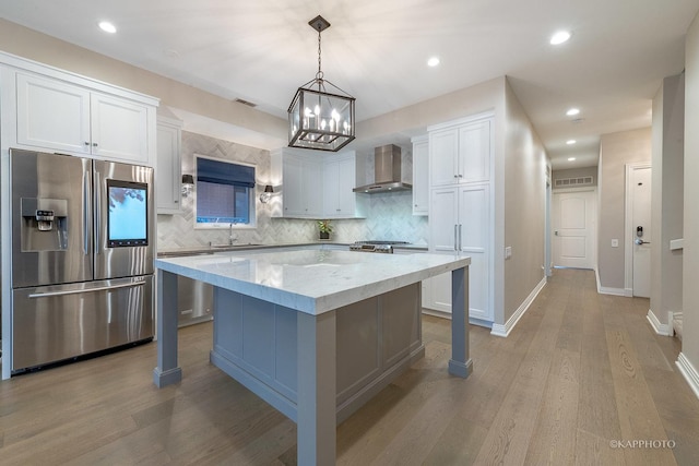 kitchen with white cabinetry, wall chimney exhaust hood, and stainless steel fridge with ice dispenser