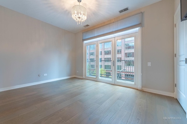 spare room featuring hardwood / wood-style flooring and an inviting chandelier