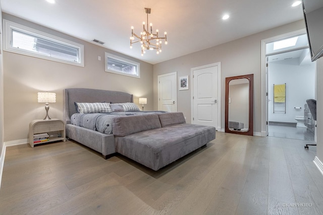 bedroom featuring hardwood / wood-style flooring, a chandelier, and ensuite bathroom