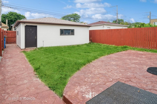 rear view of property with an outdoor structure, a yard, and a patio area