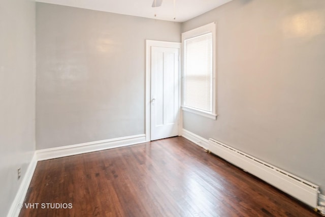 empty room with a baseboard heating unit, dark wood-type flooring, and ceiling fan