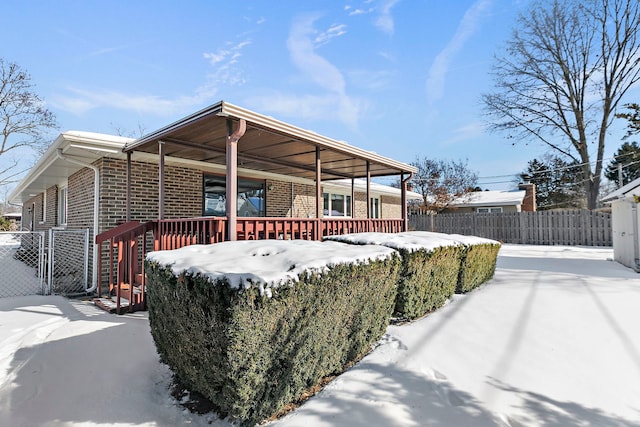 exterior space featuring covered porch, brick siding, and fence