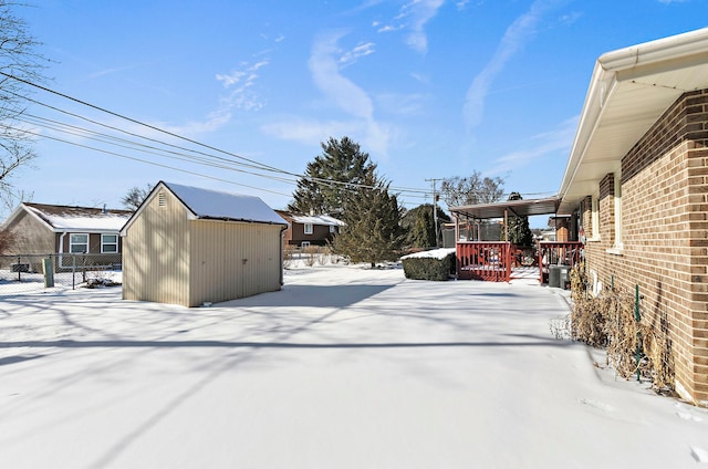 yard covered in snow featuring an outbuilding, fence, and a storage shed