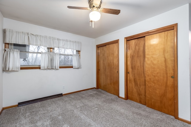 unfurnished bedroom featuring carpet, two closets, and ceiling fan