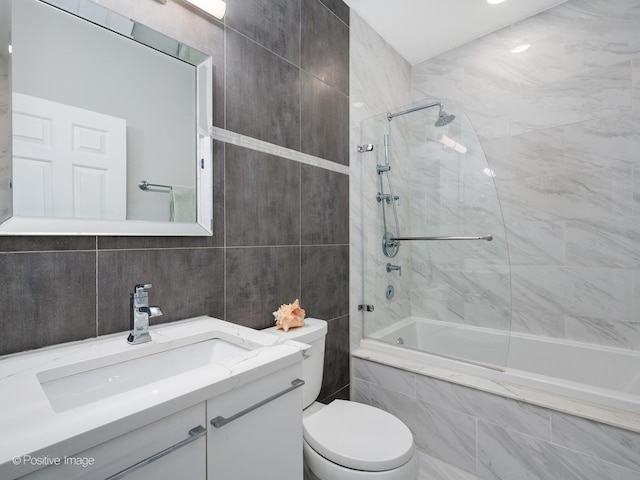 full bathroom featuring tiled shower / bath combo, vanity, tile walls, and toilet