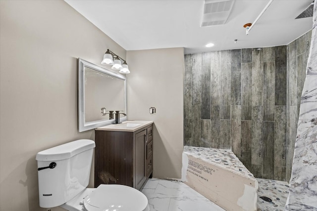 bathroom with vanity, toilet, and tiled shower