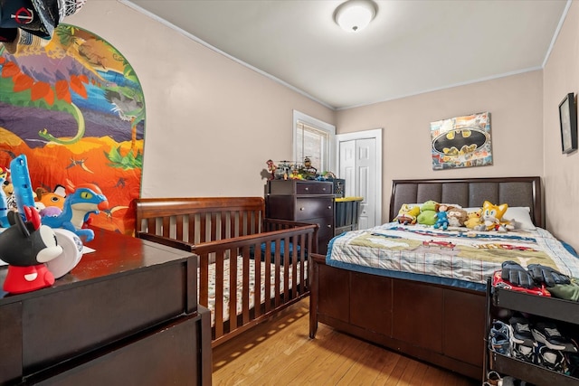 bedroom with ornamental molding, light hardwood / wood-style floors, and a closet